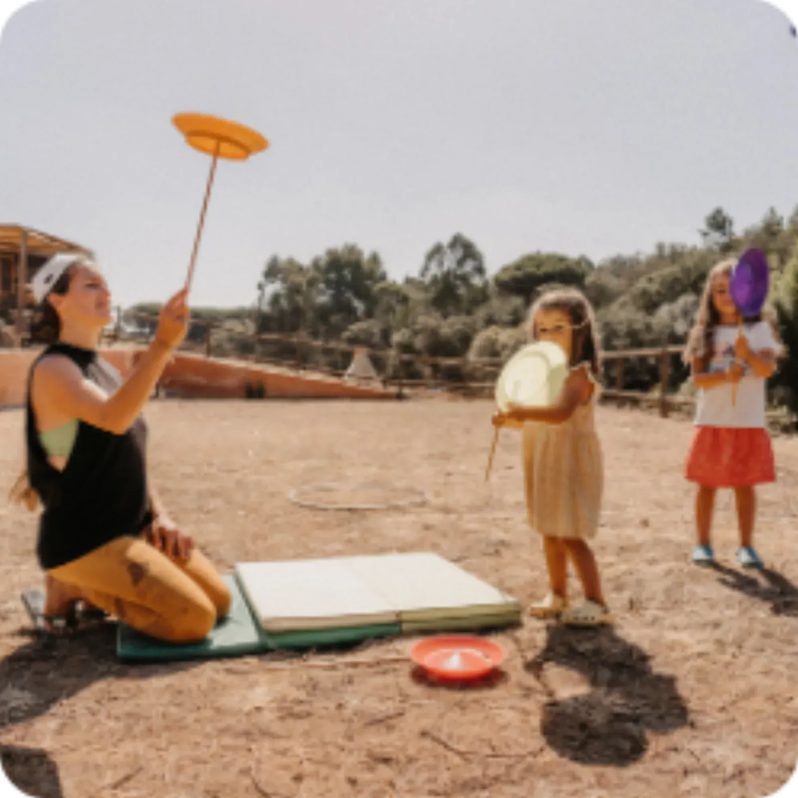 A mother spinning plates with children watching in the sun