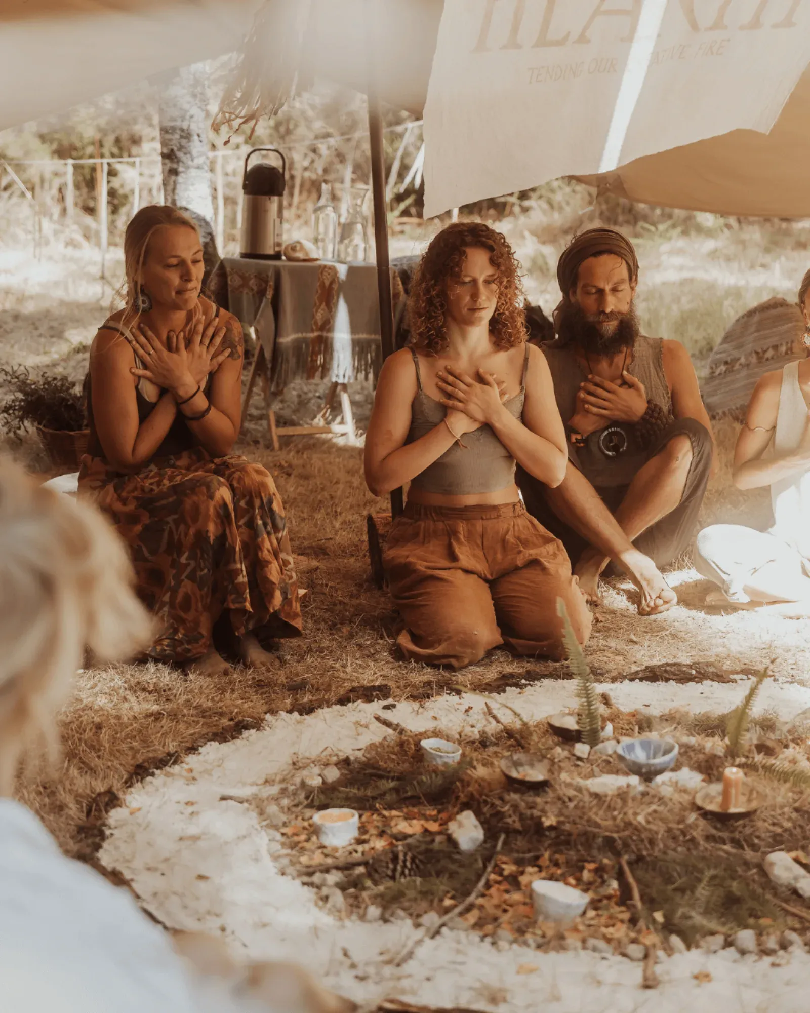 Adults sitting in a sharing circle under a canopy