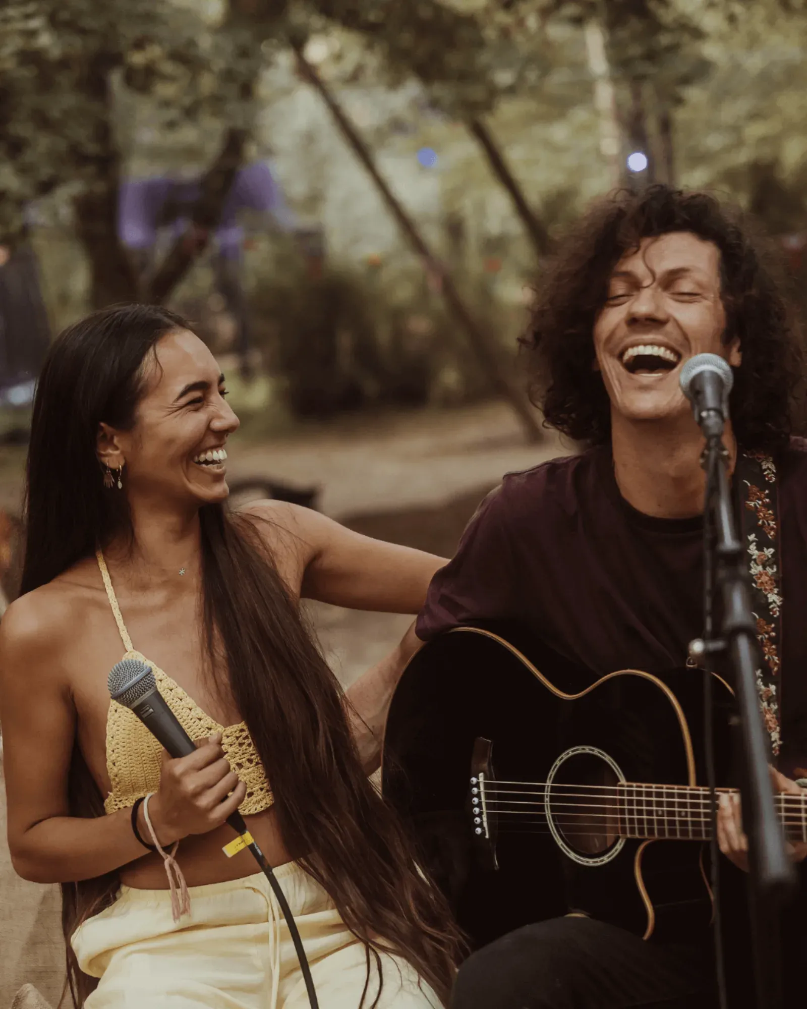 Two musicians singing and playing guitar at dusk