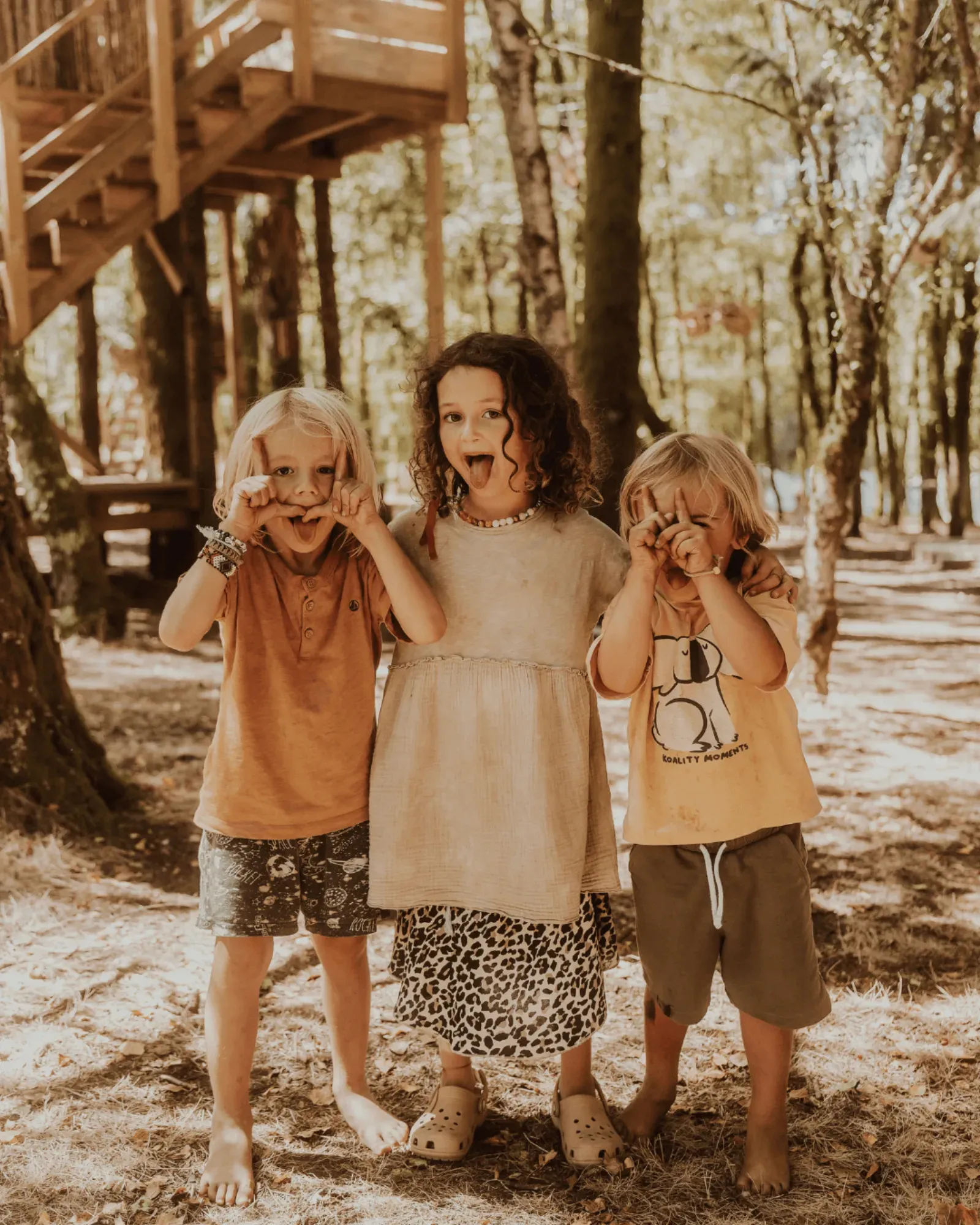 Three children pulling faces for the camera in the woods