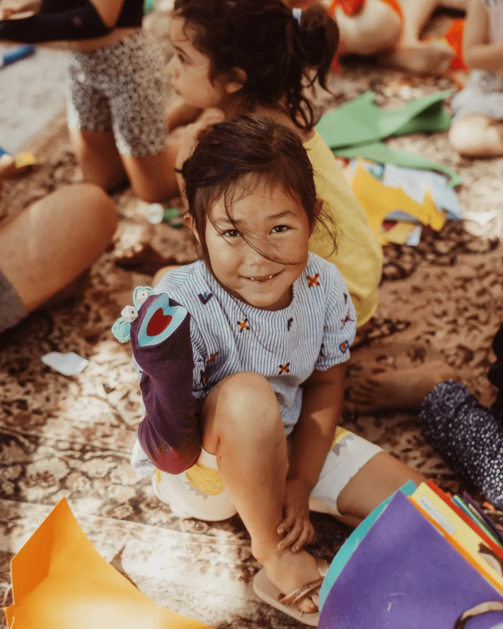 A small child laughing on the ground among colourful flags